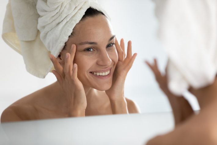After beauty home procedure woman looking at skin feels satisfied