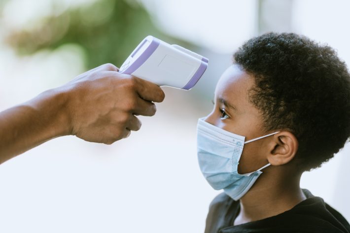 Child With Face Mask Has Temperature Taken at School